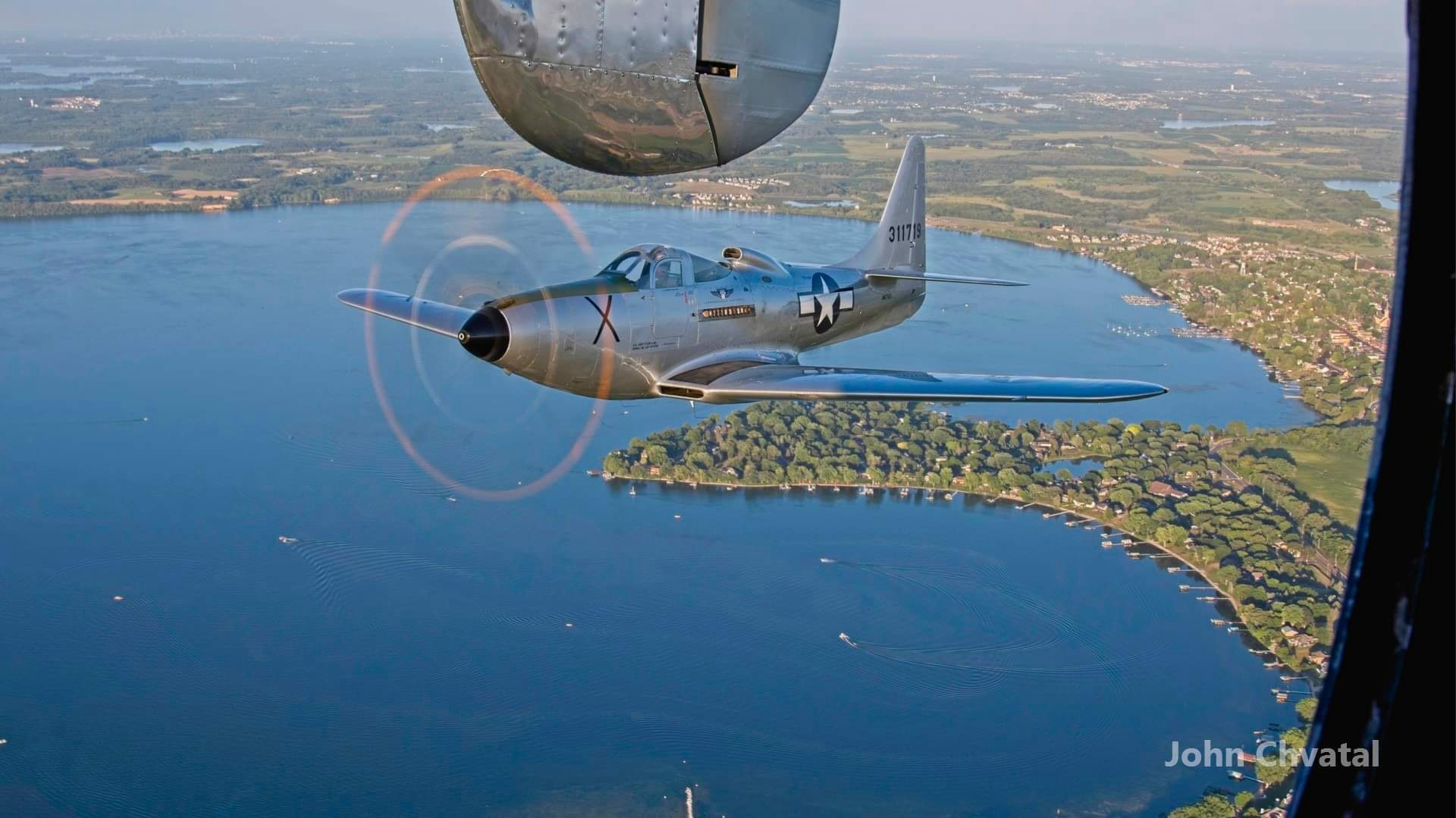 Bell P-63 Kingcobra flying in formation alongside a B-25 Mitchell bomber over Lake Waconia, Minnesota, photographed from the B-25 waist gunner position
